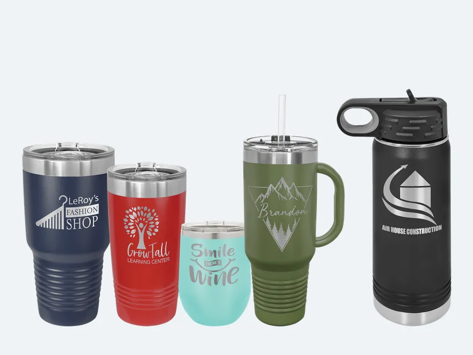Five Polar Camel cups with sample engravings: a navy 30 oz tumbler, a red 20 oz tumbler, a teal wine tumbler, an olive 40 oz travel mug with a handle and straw, and a black 20 oz water bottle