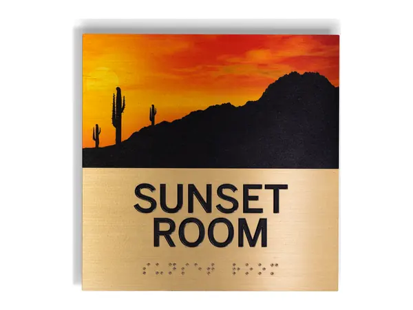 An example of a brass room sign reading SUNSET ROOM in raised letters, with braille and a full color sunset picture
