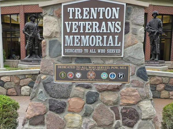 An example of a veterans memorial plaque set into a fieldstone monument, with a smaller plaque of service emblems below