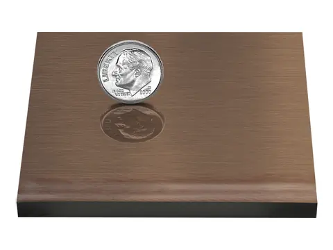 A bronze sample plate with the alternative oxidized finish, a deep even brown, with a dime on it for scale