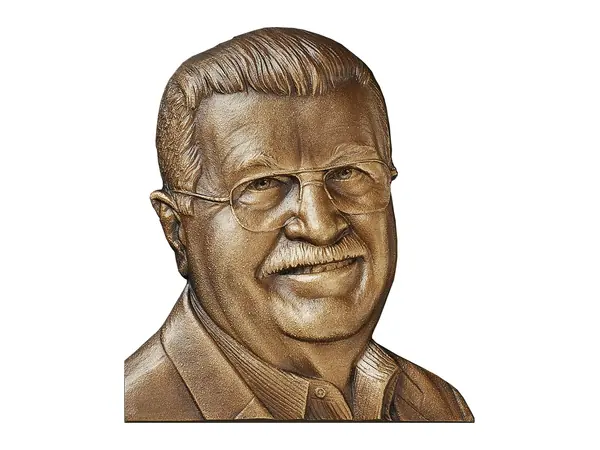 An example of a bas relief bronze portrait of a smiling man in glasses