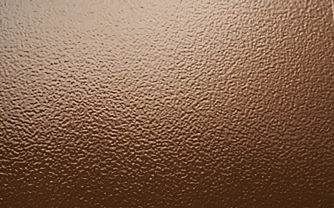 A close up of the stipple background texture on a bronze plaque